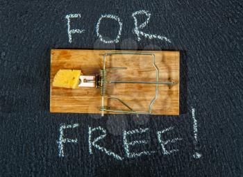 conceptual picture of a mousetrap with a piece of cheese and the inscription FOR FREE on a dark background