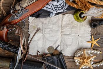 vintage pirate sword and pistol flag jolly roger and other medieval equipment lie on an empty paper scroll