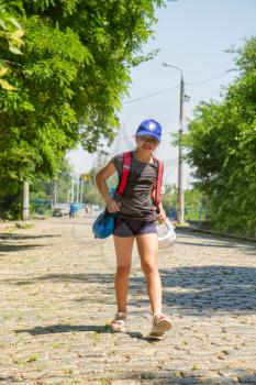 little girl athlete goes to martial arts training on an empty street with a backpack with equipment