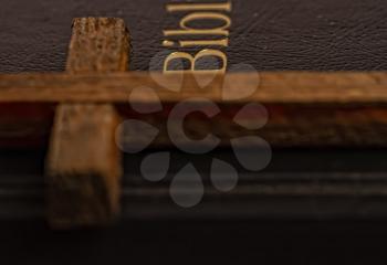 Old closed cover holy bible and simple wooden cross close up