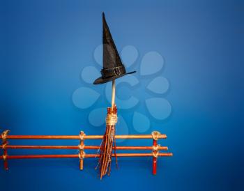 Classic witch black pointed hat and flying broom stand by the fence