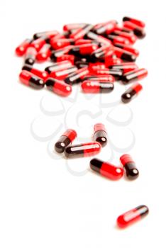 scattered black-red capsules of pills on a white background