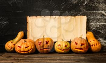 Several festive Halloween pumpkins with different emotions on the background of an old shabby blank paper sheet with place for text