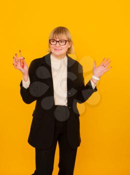 Business woman in a suit rejoices on a yellow background
