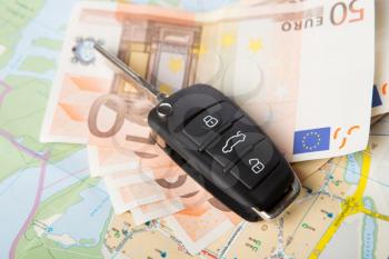 Car rental concept - car key and money on the road map