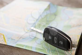 Car rental concept - car key on the road map