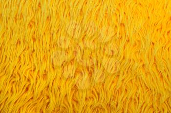 Closeup image of yellow shaggy carpet.