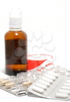 Small tablets and other medicaments on a white background.
