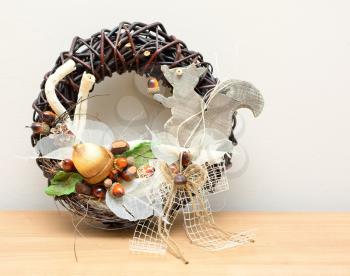 Closeup shot with autumn decoration on the table. Wreath with squirrel and acorns.