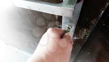 Close-up of hand with key unlocking the metallic door.