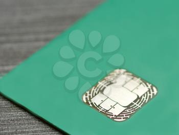 Close-up of electronic EMV chip in green credit card.