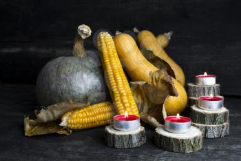 Pumpkin, Corncob, autumn leaves and burning candles Decoration on a wooden table