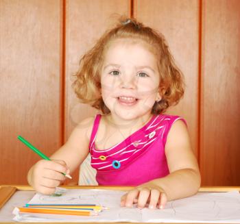 Happy little girl drawing with crayons