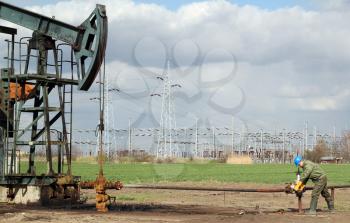 oil field with pump jack and worker