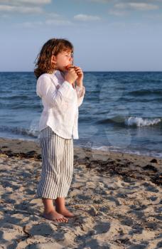 beautiful little girl play pan pipe on beach