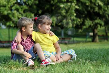 boy and little girl sitting on grass in park