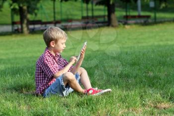 boy sitting on grass and play with tablet pc