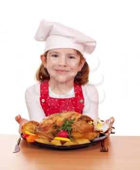 beautiful little girl cook with roasted chicken on table