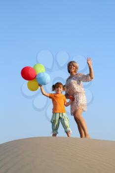 happy mother and daughter with balloons on beach