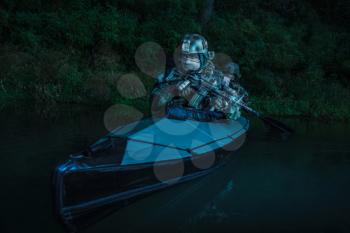 Special forces men with painted faces in camouflage uniforms paddling army kayak. Boat moving calmly across the river, diversionary mission, twilight