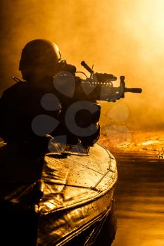 Backlit silhouette of special forces marine operators in military kayak on fire explosion background. Battle operation
