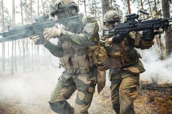 Norwegian Rapid reaction special forces FSK soldiers in field uniforms in action in the forest fog covering each other, cropped
