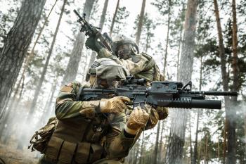 Norwegian Rapid reaction special forces FSK soldiers in field uniforms in action in the forest fog covering each other. Low angle view