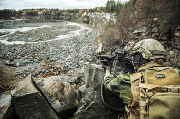 Norwegian Rapid reaction special forces FSK soldier in field uniforms in ambush among the rocks guarding perimeter waiting enemy