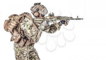 Operator of Russian special operations forces with kalashnikov assault rifle, military backpack and combat helmet shooting a weapon. Studio shot, isolated on white background, profile view