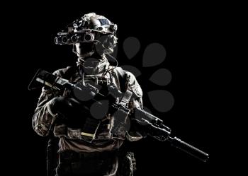 Modern army special forces equipped soldier, anti terrorist squad fighter, elite mercenary armed assault rifle, standing in darkness with night vision goggles on helmet, studio portrait, copyspace