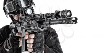 Police tactical group shooter, SWAT, anti-terror team member in black uniform and helmet aiming assault rifle with optical sight and flashlight, shooting with service weapon close up isolated portrait