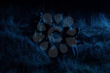 Commandos group, army special operations tactical group, military patrol team marching in field loaded with ammunition, sneaking in darkness, carefully and quiet moving in line during night mission