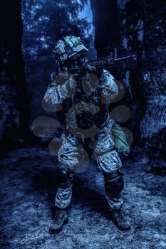 US Marine Corps Soldier in action among the rocks under cover of darkness. Dark gloomy night