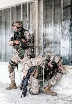 Marines assault team fighting in city conditions, breaking under intensive enemy fire. Army sergeant screaming orders while shooter crouching down after bullet hitting and breaking glass near his head