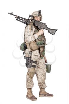 Studio shoot of army, marine machine gunner in camouflage combat uniform and body armor, standing with machine gun on shoulder, holding ammunition box in hand and looking at camera, isolated on white