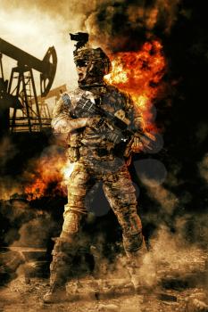 Army soldier in action. Great explosion with fire and smoke billows. Oil rig on the background
