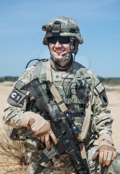 Portrait of United states airborne infantry man with arms, camo uniforms dress. Combat helmet on, tactical light, radio microphone on his mouth