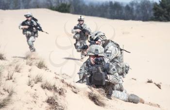 Team of United states airborne infantry men with weapons in action in desert