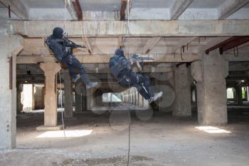 Special forces operators during assault rappeling with weapons 