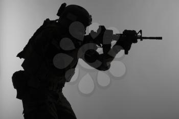 United states Marine Corps special operations command Marsoc raider with weapon aiming a gun. Silhouette of Marine Special Operator gray background