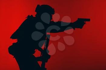 United states Marine Corps special operations command Marsoc raider with weapon aiming pistol. Silhouette of Marine Special Operator red background