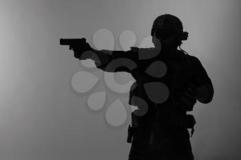 United states Marine Corps special operations command Marsoc raider with weapon aiming pistol. Silhouette of Marine Special Operator gray background