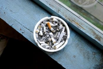 Ashtray full of stubs on a wooden window sill.