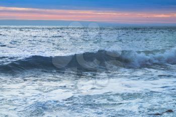 Sea landscape with big waves against sunset