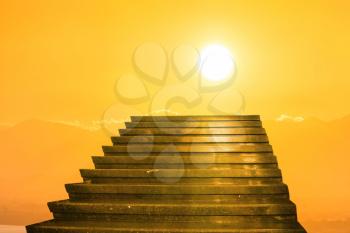 Stairway to heaven. Stairs towards sun on the orange sunset with clouds