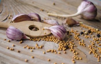 Cloves of garlic, mustard seeds and spoon on wooden board. Rustic style garlic on vintage wooden background. Fresh garlic clove. Garlic bulbs.