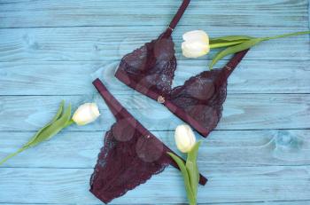 Women's lingerie on the wooden background. Top view shot of fashionable women's underwear. Close-up of transparent crimson silk panties with lace and bra.