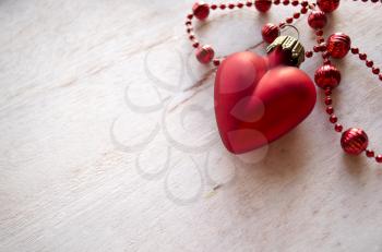 Christmas composition with Christmas fir-tree toy red heart and necklace on wooden background. Winter decoration. Valentines day backglound.