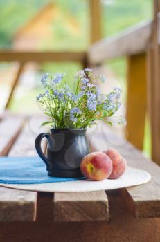 Still life with wildflowers and peaches. Flowers in vase with peach fruit on a table in a summer cottage