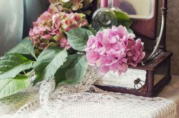 Still life of hydrangea, ancient mirror on knitted crocheted napkin. Vintage composition in the style of chebbishik.